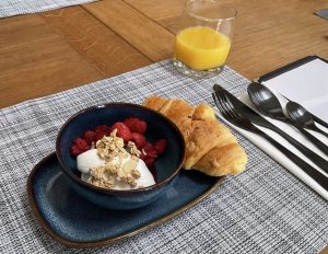 Continental breakfast at Craighall Steading B&B with fresh raspberries, yoghurt, granola, croissant, and orange juice.