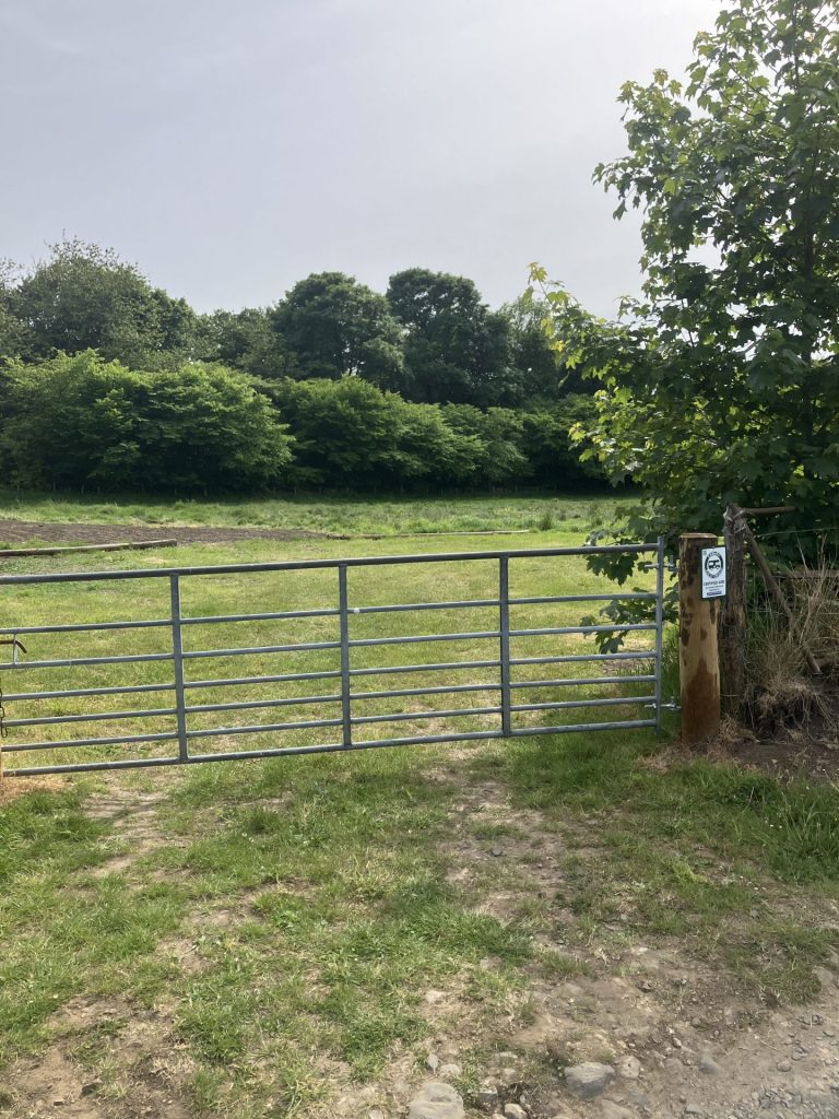 a metal-gated entrance to the field where campervans can park